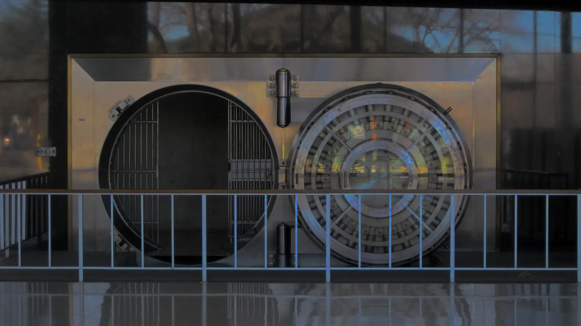 Stainless steel bank vault with its round door swung open behind a railing